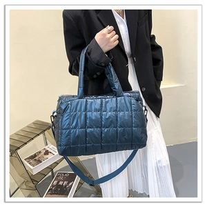 Detail of dark blue glossy quilted puffer tote bag with rectangular stitching and metallic texture