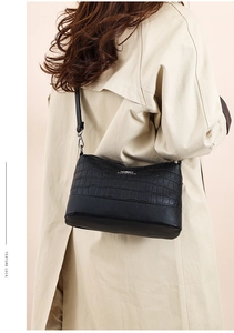 Detail of black crocodile texture patchwork and sleek finish on a women's shoulder bag