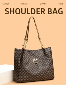 Detail of retro printed tote bag featuring gold M logo and chain leather shoulder strap
