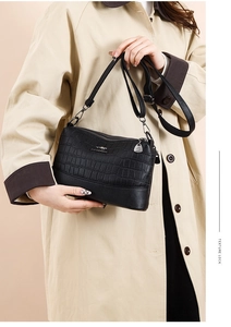 Detail of black faux leather shoulder bag with crocodile texture and metal kangaroo logo