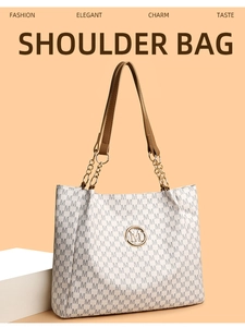 Close-up of monogram pattern tote bag with brown leather handles and gold M logo