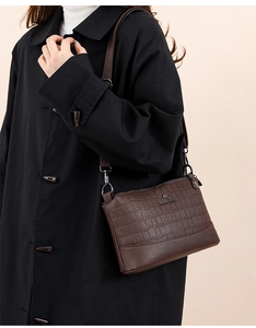 Detail of dark brown faux crocodile leather crossbody bag with metallic kangaroo logo