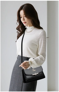 Détail de la texture tressée et boucle florale sur le sac bandoulière noir