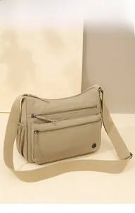 Detail of khaki nylon shoulder bag featuring multiple zipper pockets and wide strap