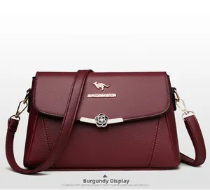 Details einer weinroten Ledertasche mit goldenem Känguru-Logo und floralem Verschluss