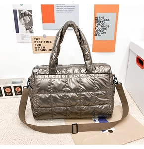 Detail of shiny brown quilted puffer bag with thick handles and adjustable strap