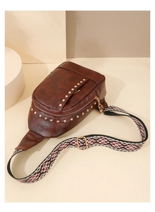 Détail du sac de poitrine en cuir clouté marron avec bandoulière ethnique et boucles dorées