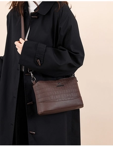 Detail of dark brown leather crossbody bag featuring crocodile and litchi texture blend