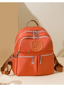 Detailansicht eines orangefarbenen Nylon-Rucksacks mit Reißverschlusstaschen und Herzlogo