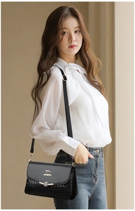 Gros plan sur le sac en cuir noir avec texture tressée, logo kangourou et fermoir fleur