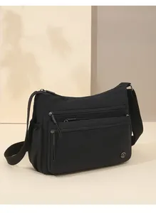 Detailed view of a black waterproof nylon crossbody bag with multiple zipper pockets