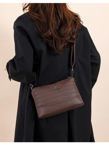 Detail of brown crossbody bag with crocodile texture and metal kangaroo logo