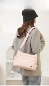 Side view of a pink lightweight nylon crossbody bag with multi-pocket design on model