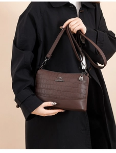 Detail of dark brown faux crocodile leather texture and metallic kangaroo brand logo