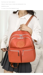 Detailansicht eines orangefarbenen Nylonrucksacks mit Reißverschlüssen und Kleeblatt-Logo