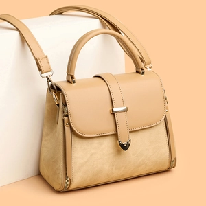 Khaki leather crossbody bag with top handle and heart-shaped metal buckle in 45-degree view