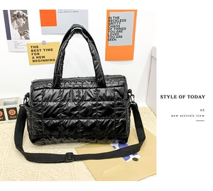 Detail of black quilted puffer tote bag with wide handles and adjustable shoulder strap