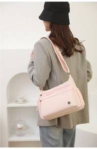 Light pink nylon crossbody bag with multi-zipper pockets and adjustable shoulder strap