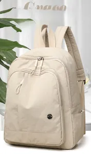Detail of light beige oxford backpack with silver zippers and metal M FASHION logo plaque