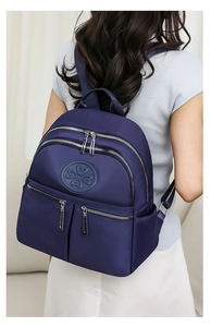 Detailansicht des blauen Nylon-Rucksacks mit silbernen Reißverschlüssen und vielen Taschen