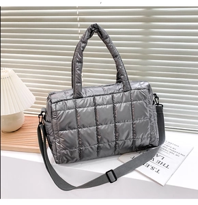 Detail view of metallic silver quilted tote bag with adjustable woven shoulder strap