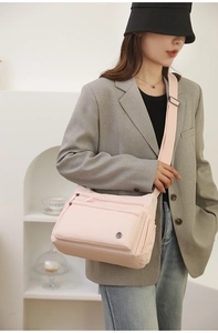 Detail of light pink nylon crossbody bag with multiple zippers and wide strap