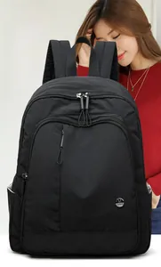 Close-up of lightweight black oxford backpack featuring durable metal logo and zippers