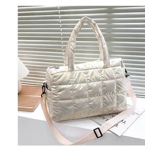 Detailed close-up of a white quilted tote bag with glossy fabric and detachable strap