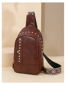 Détail du sac bandoulière en cuir marron avec rivets dorés et sangle tissée ethnique
