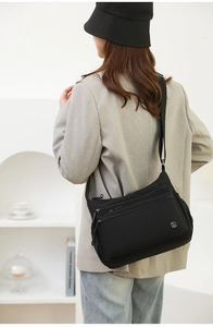 Fashionable black nylon crossbody bag with multi-pocket design shown on stylish model
