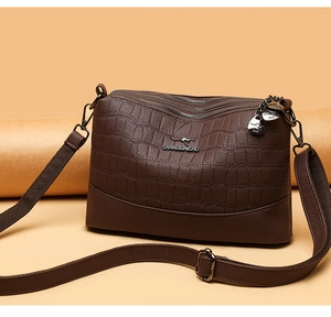 Close-up of brown crocodile texture leather and triple zipper design on the crossbody bag