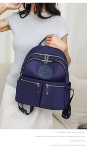 Detail eines dunkelblauen Nylon-Rucksacks mit mehreren Reißverschlusstaschen und Kleeblatt-Logo