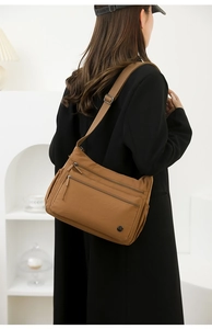 Detail view of brown nylon crossbody bag featuring double front zippers and a metal logo