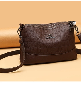 Detail of dark brown faux crocodile leather texture and kangaroo metal logo on crossbody bag