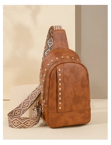 Détail du sac de poitrine en simili cuir marron avec clous dorés et sangle tissée