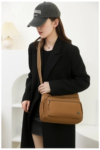 Detail of a brown multi-zipper nylon crossbody bag on model showing large capacity
