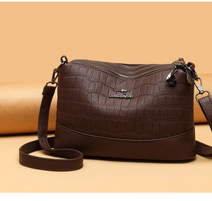 Close-up of triple zipper pockets on a brown faux crocodile leather crossbody bag