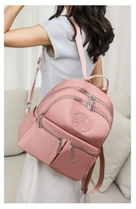 Seitenansicht des leichten rosa Nylonrucksacks mit mehreren Reißverschlussfächern am Modell
