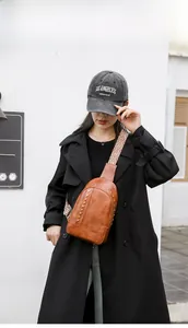 Détail du sac bandoulière en cuir marron vintage avec rivets dorés et sangle ethnique