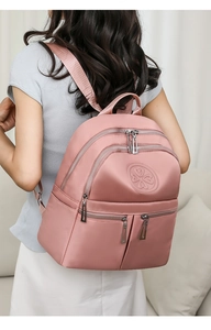 Detailansicht eines rosa Nylon Rucksacks mit mehreren Taschen und Kleeblatt-Prägung