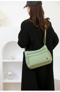 Detail of light green waterproof nylon shoulder bag featuring multiple zipper pockets