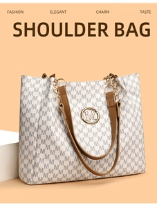 Detail of white tote bag featuring grey M monogram print and brown leather handles