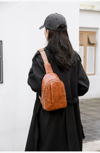 Sac bandoulière rétro en cuir marron avec clous dorés et sangle tissée sur modèle