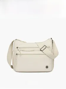 Close-up of beige nylon crossbody bag featuring multi-zipper pockets and adjustable strap