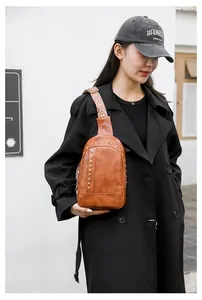 Sac bandoulière marron à rivets avec sangle bohème porté par une femme en extérieur