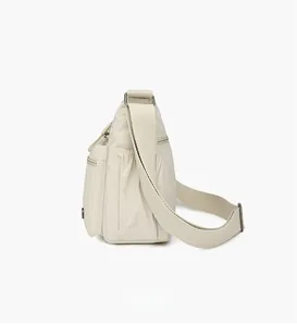 Side view of cream nylon crossbody bag showing side zipper pocket and elastic pouch