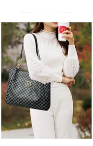 Outdoor model shot of black tote bag with M monogram print and chain strap
