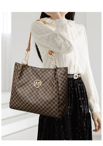 Classic tote bag with all-over M print and gold chain strap shown on a female model