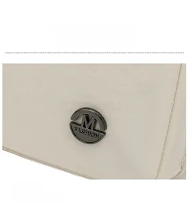 Macro shot of nylon fabric texture and round metal M Fashion logo on beige shoulder bag