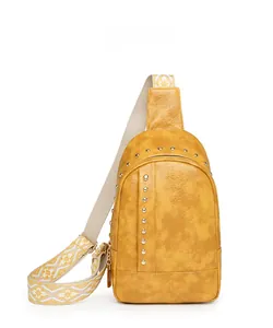 Détail du sac bandoulière en cuir jaune avec rivets dorés et sangle brodée ethnique